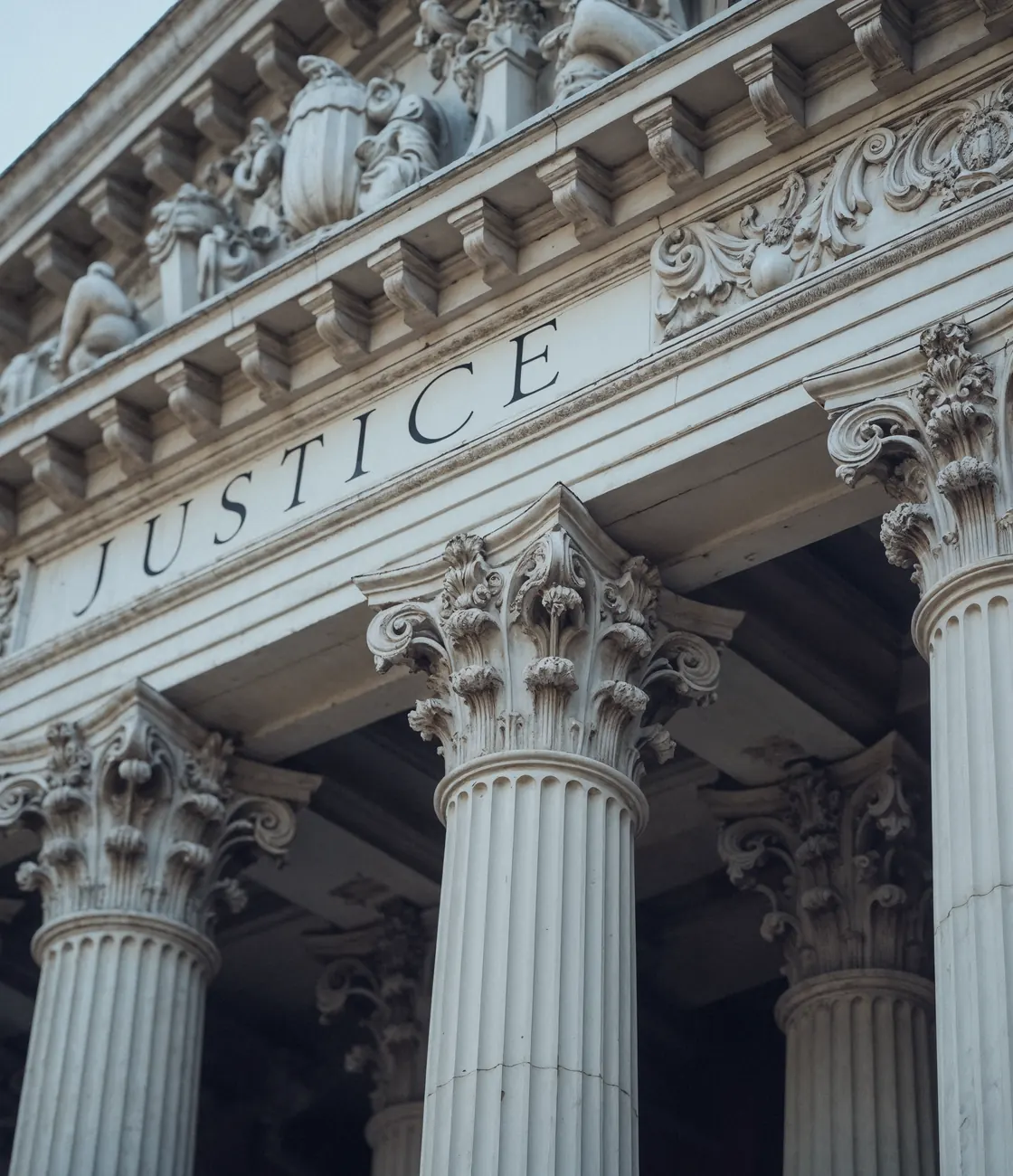 Courthouse columns beneath an engraved Justice frieze