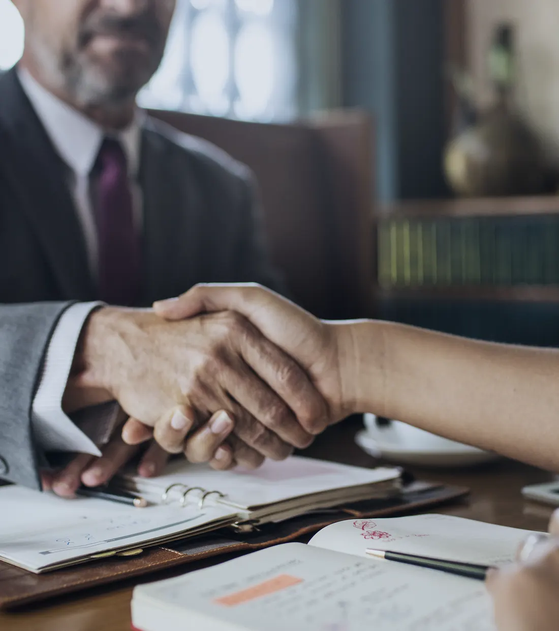 An attorney shaking hands with a client across a desk